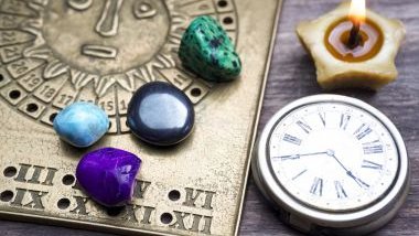 Imagem de vários elementos como pedras, cristais, velas e bússola sobre uma mesa de madeira, simbolizando a previsão do futuro por meio da astrologia