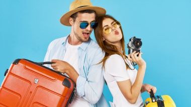 Imagem de um casal se preparando para viajarem. Ambos usam óculos de sol, seguram suas malas nas cores laranja e amarelo e estão felizes.