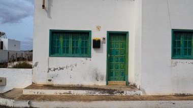 Imagem de uma casa branca com portas e janelas na cor verde.