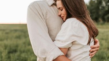 Imagem de um casal se abraçando e ao fundo um lindo campo verde.