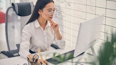 Imagem de uma mulher que é chefe concentrada em sua mesa de trabalho olhando para o computador.