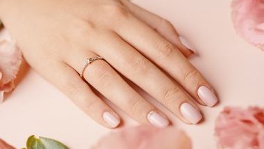 Imagem das mãos de uma mulher com as unhas esmaltadas e uma aliança de ouro com brilhantes no dedo anelar esquerdo.