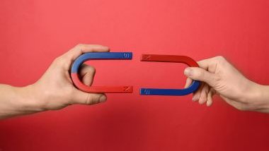Imagem das mãos de um homem e de uma mulher, segurando um imã, simbolizando o magnetismo.