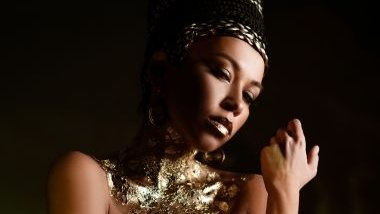 Imagem de uma mulher parda, usando uma roupa dourada e um adorno dourado na cabeça, simbolizando a pombagira Rainha.