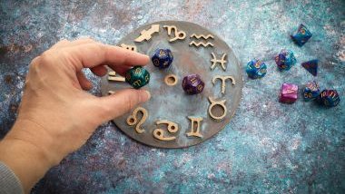 Imagem de uma mandala astrológica e da mão de uma pessoa colocando algumas pedras coloridas sobre ela.