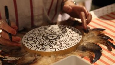 Imagem de uma mulher fazendo a leitura em uma mandala astrológica.