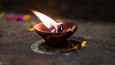Imagem de uma tigela de barro com uma vela acesa dentro dele, simbolizando um ritual do Candomblé, denominado Ebó.