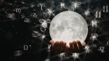 Há as mãos de uma pessoa segurando uma bola de cristal. Ao redor da bola, há os símbolos dos signos do zodíaco.
