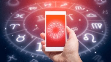 Na imagem, há uma Roda do Zodíaco com os símbolos dos signos e há um celular reproduzindo a mesma imagem da roda.