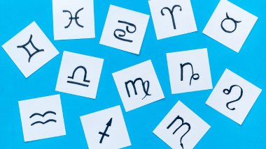 9dreamstudio / Getty Images / Canva No foco da imagem, há papéis cortados com as imagens dos símbolos dos signos do zodíaco.