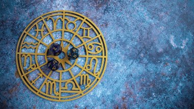 Nambitomo / Getty Images / Canva No foco da imagem, há uma Roda do Zodíaco e, em cima dela, há três dados com os símbolos dos signos e números.