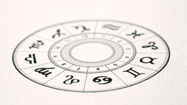 No foco da imagem, há uma Roda do Zodíaco desenhada em um papel.