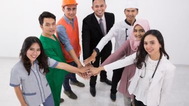 Imagem de um grupo de pessoas, homens e mulheres, com as mãos mãos sobrepostas, cada uma delas com uma profissão diferenciada.