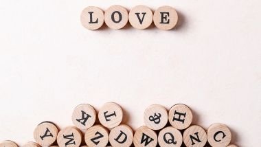 Imagem de várias pedras redondas em madeira e cada uma  delas traz uma letra do alfabeto. Acima da imagem, temos a palavra Amor, escrita em inglês.