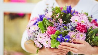 Imagem de uma mulher segurando em seus braços vários tipos de flores.