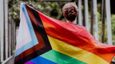Imagem de uma mulher carregando a bandeira LGBTQIAPN+, simbolizando os personagens mais marcantes de cada signo.