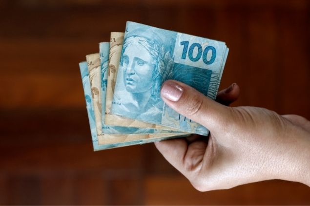 mão segurando notas de dinheiro
