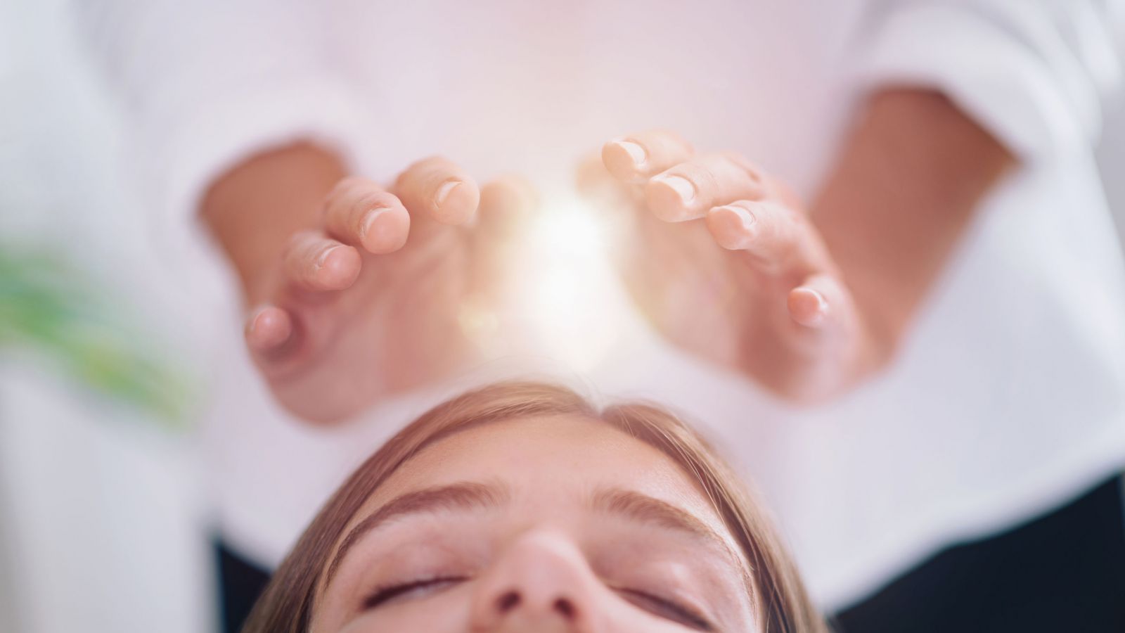 Mulher de olhos fechados recebendo tratamento Reiki