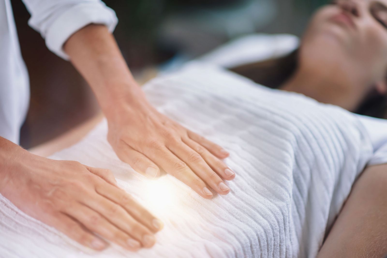 Mulher deitada em uma maca recebendo tratamento Reiki