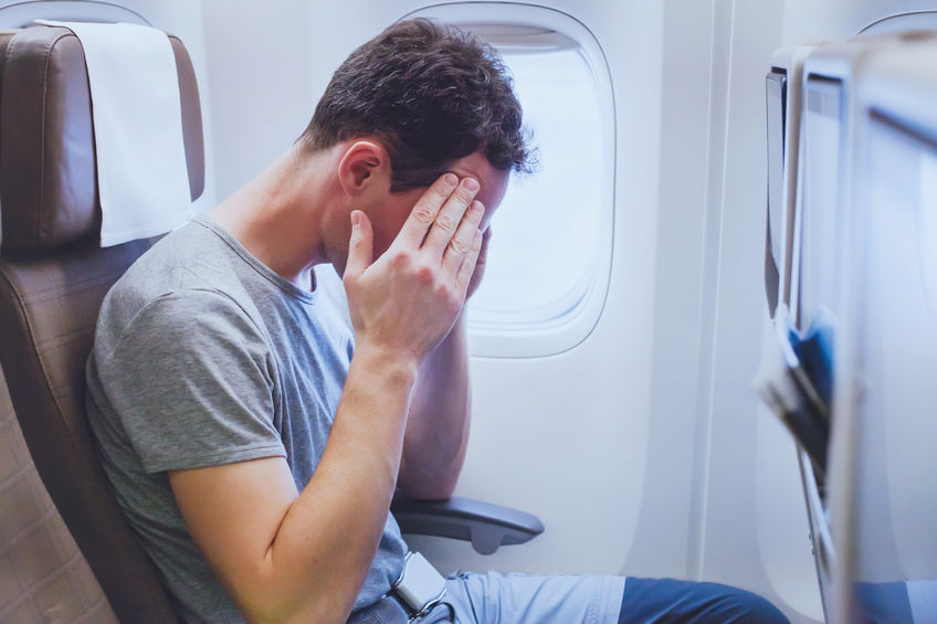 Homem em poltrona de avião com expressão tensa