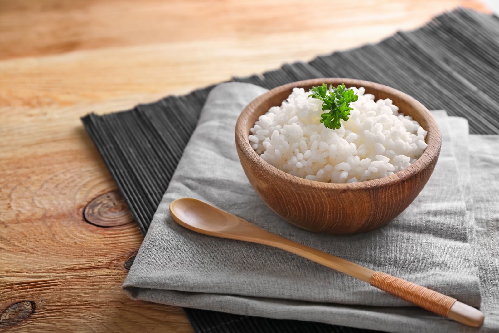 Arroz cozido em um potinho ao lado de uma colher