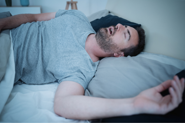 Homem dormindo na cama de boca aberta e roncando
