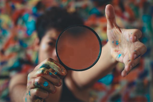 pessoa pintada de tinta segurando uma lupa