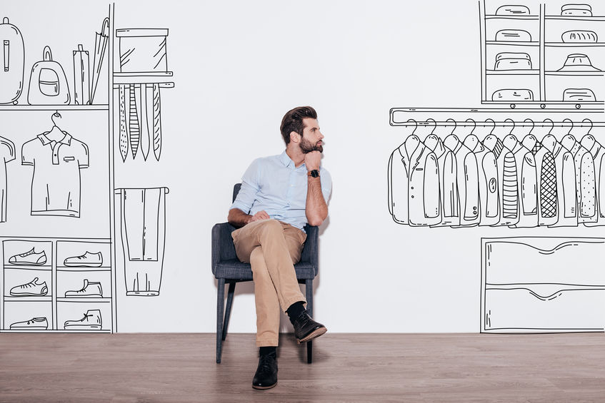 Homem olhando para um desenho de roupas na parede