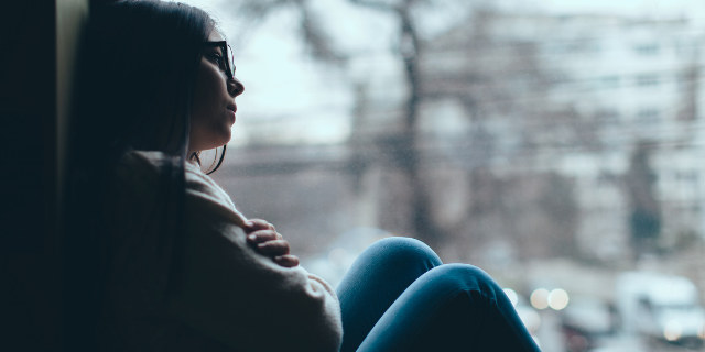 Mulher triste olhando melancólica pela janela