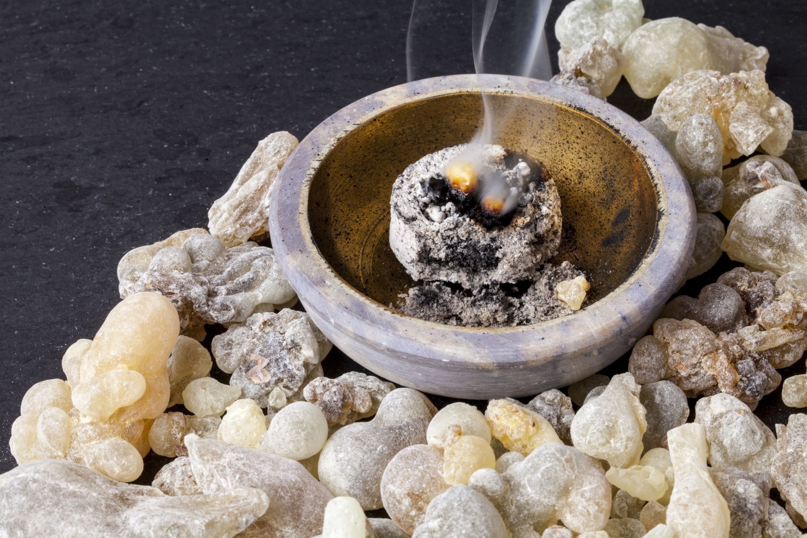 Incenso aceso com fumaça ao lado de algumas pedras
