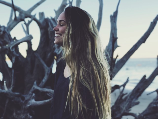 Mulher branca sorrindo numa praia.