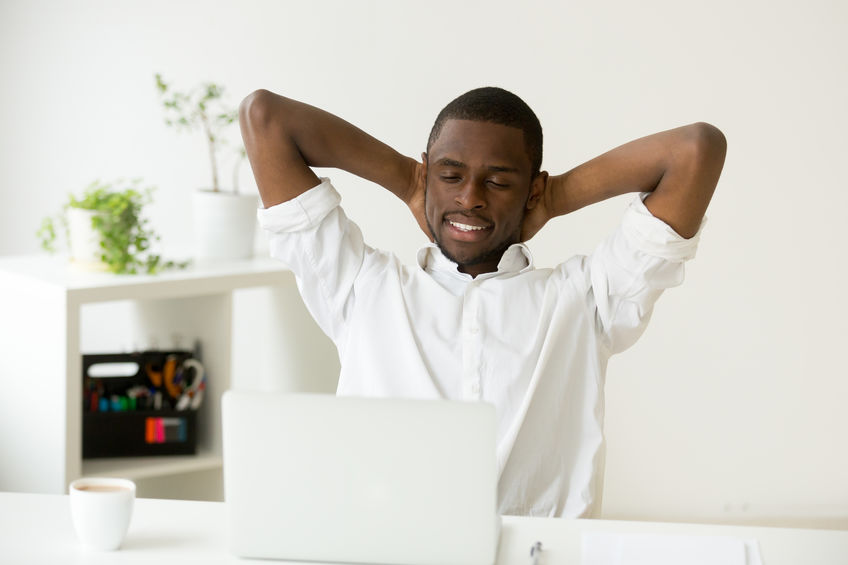 Homem relaxando em cadeira com os dois braços atrás da cabeça