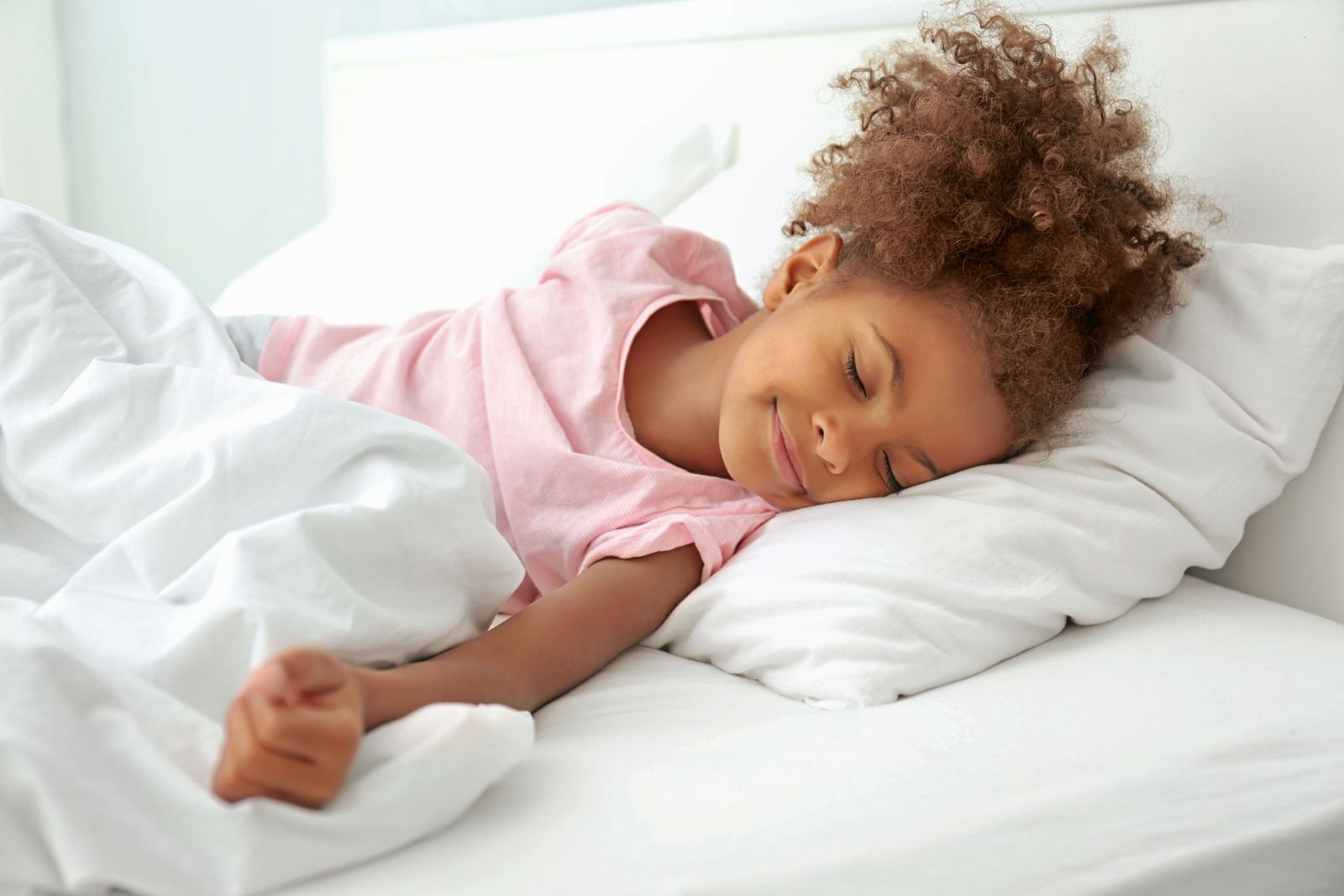 Criança dormindo na cama sorrindo