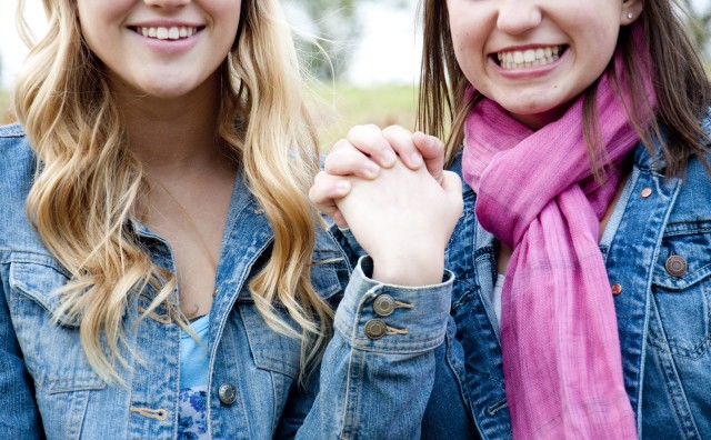 Mulheres brancas com as mãos juntas.