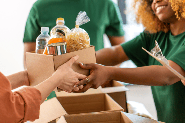  Mulher entregando caixa de alimentos em trabalho voluntário. 