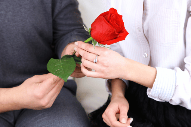 Homem dando uma flor para uma mulher. 