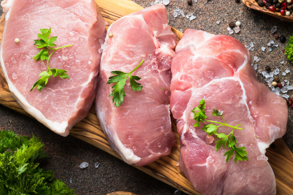 Carne de porco crua em cima de uma tábua de madeira