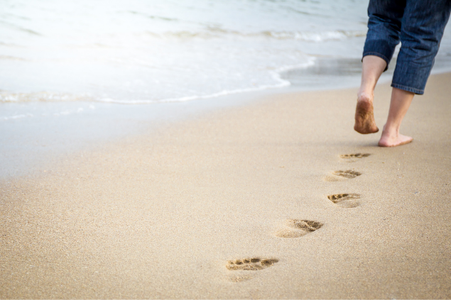 Pernas de um homem caminhando na praia