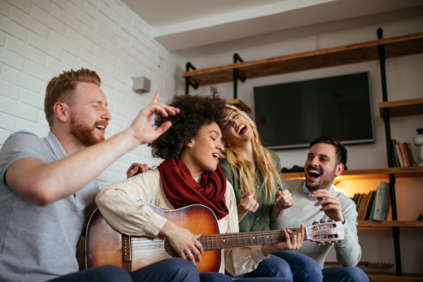 Mulher tocando violão enquanto 3 amigos ao redor cantam