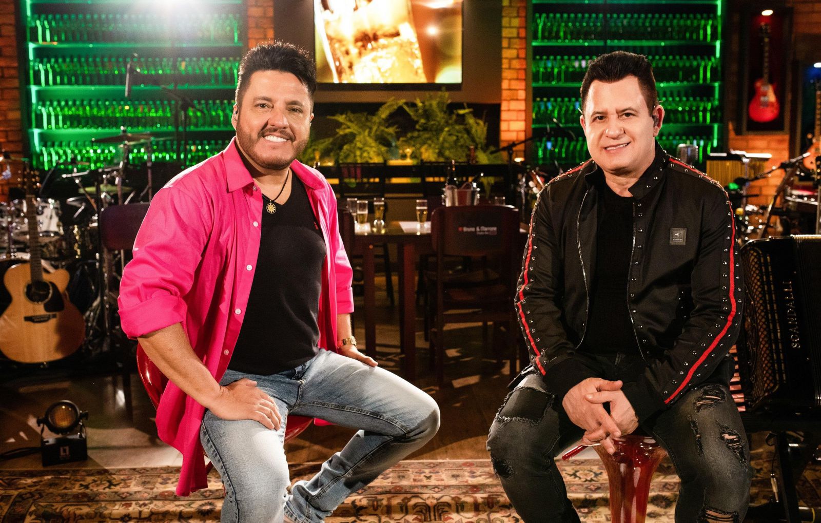 Bruno e Marrone sentados em um banco sorrindo olhando para frente
