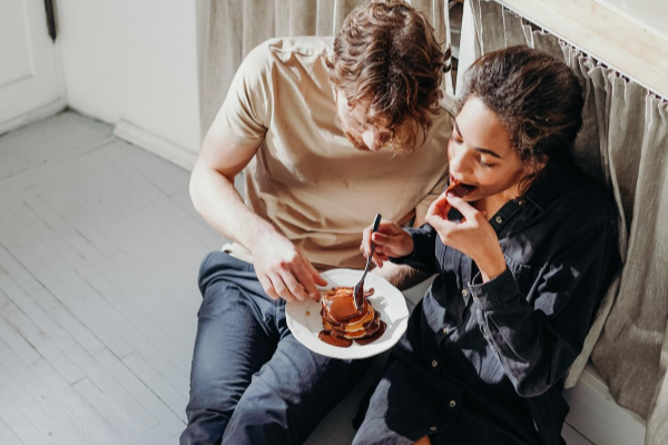 Casal sentado no chão comendo panquecas