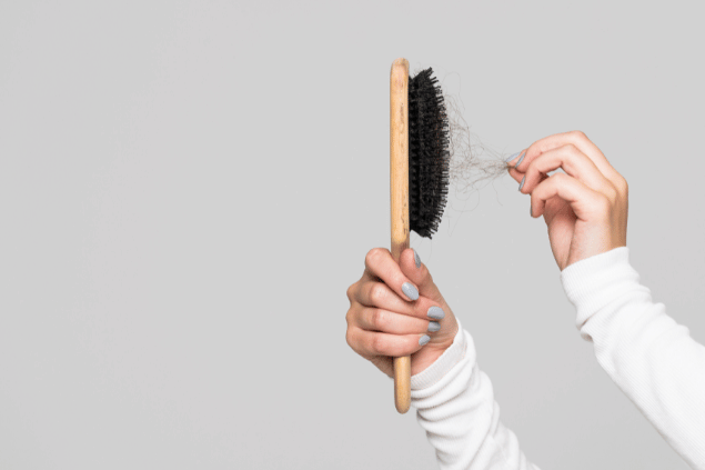 Mãos brancas tirando cabelo da escova. 