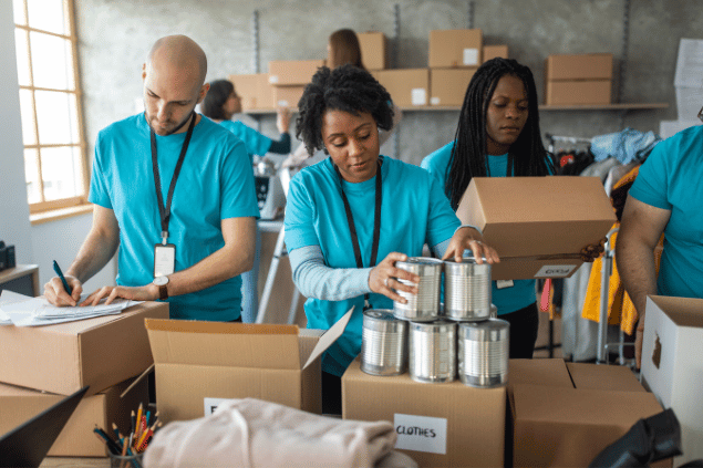 Voluntários empacotando doações em caixas de papelão. 