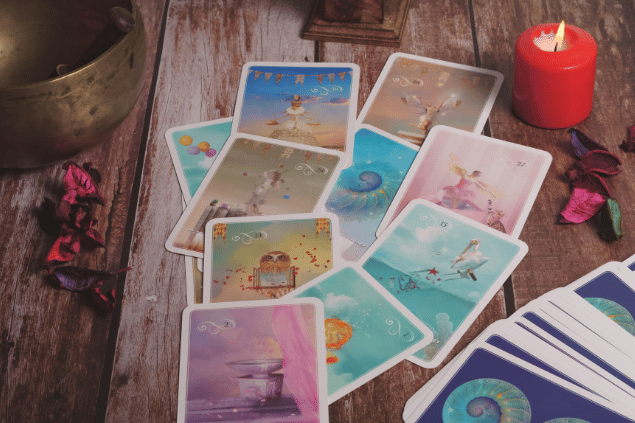 Algumas cartas de Tarot estão em destaque na imagem. Ao lado, há uma vela e outros objetos.