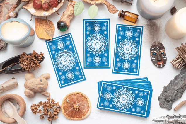 Algumas cartas de Tarot viradas para baixo estão em destaque na imagem. Ao lado, há velas e outros objetos.