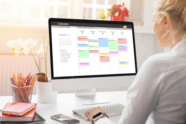 Mulher usando calendário no computador, para organizar sua rotina. 