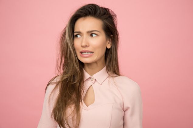 imagem de uma mulher com semblante de insegurança em um fundo rosa