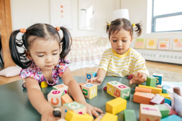 Imagem de duas meninas brincando com blocos de letras
