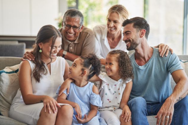 Imagem de uma família reunida sorrindo, sentados no sofá