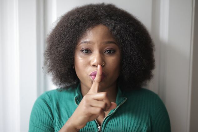 Mulher fazendo o sinal de silêncio com a mão